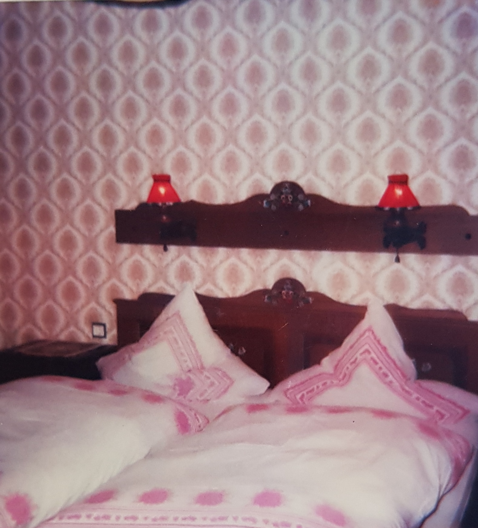 Doppelbett mit rustikaler Bemalung und Holzbrett mit Lampenschirmen an der Wand
